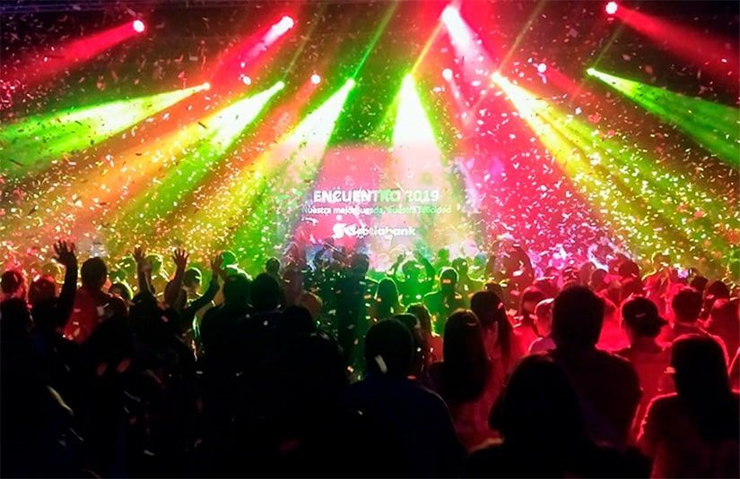 Una multitud de personas baila frente a un escenario en un concierto.