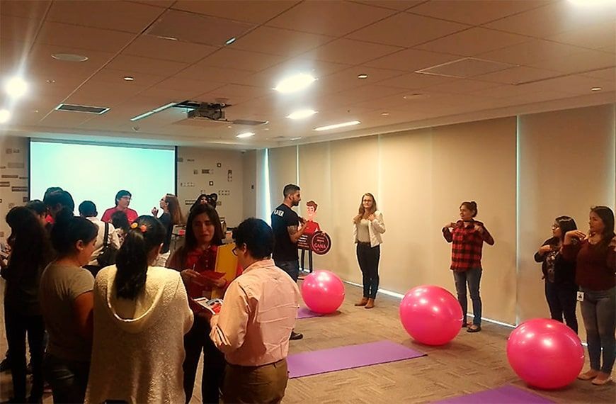 Un grupo de personas está parada alrededor de pelotas de ejercicio rosas en una habitación.