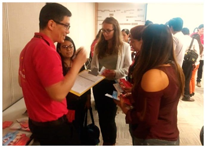 Un hombre con una camisa roja está hablando con un grupo de personas.
