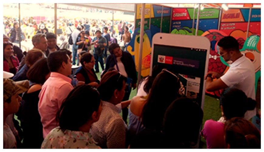 Un grupo de personas está parada alrededor de un gran teléfono móvil.