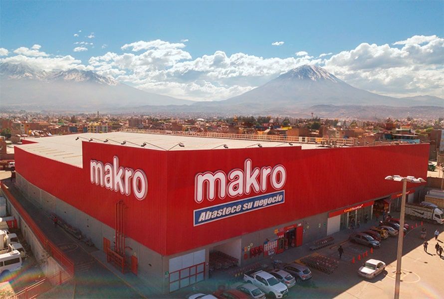 Una vista aérea de un supermercado Makro con autos estacionados frente a él.