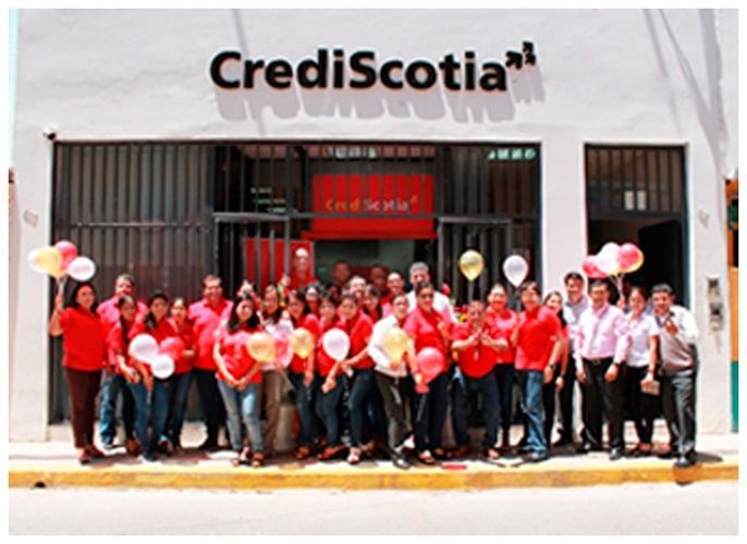 Un grupo de personas paradas frente a un edificio que dice CrediScotia