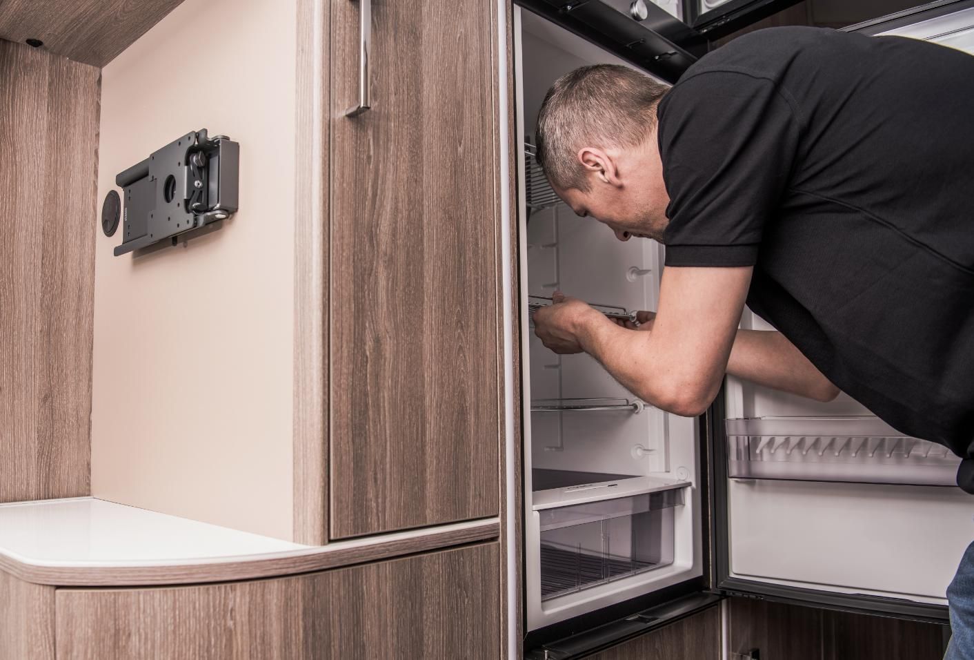 A Man Is Opening a Refrigerator Door in A Camper Van — JDG Refrigeration & Air in Ballina, NSW