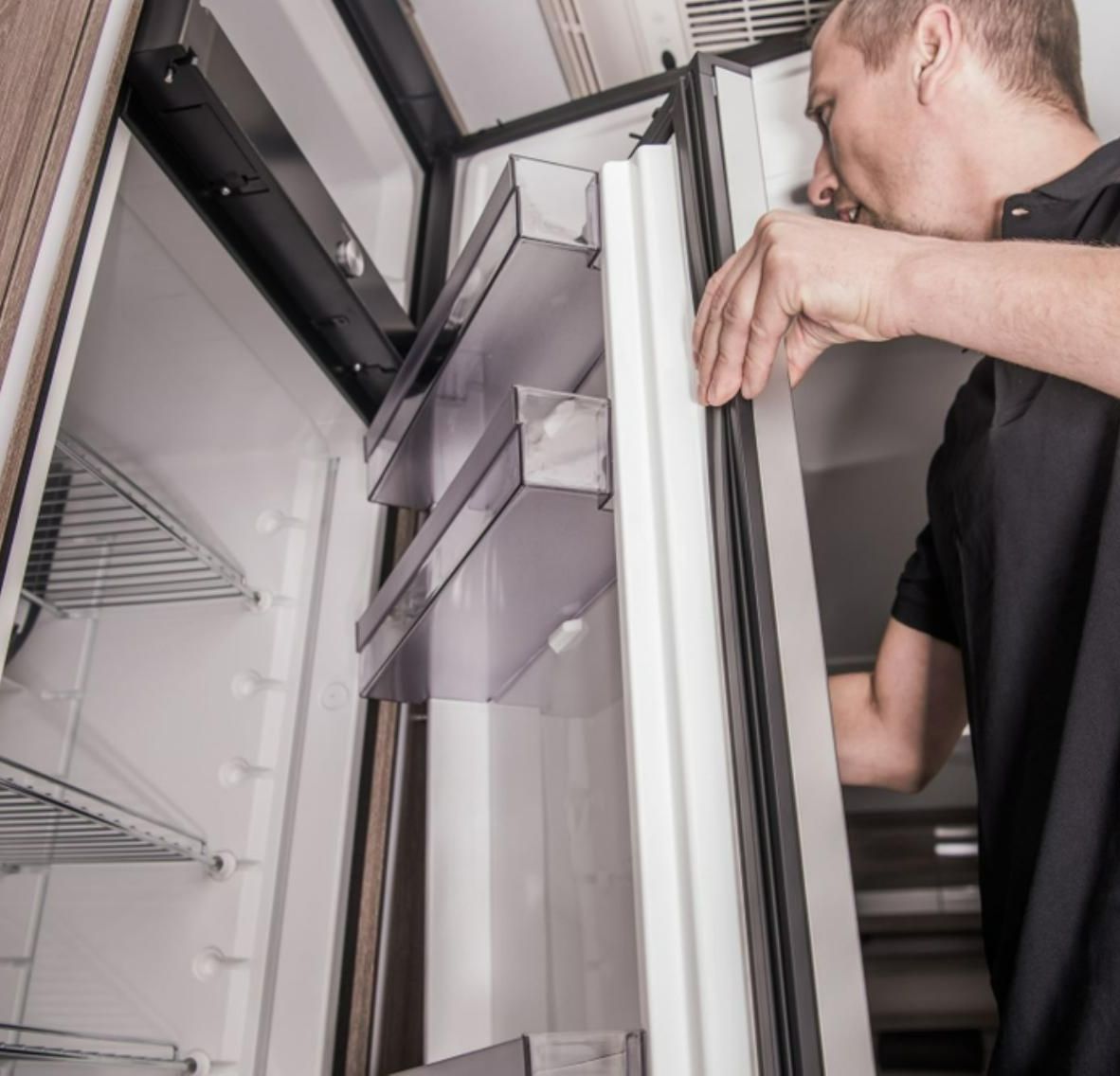 A Man in A Black Shirt Is Opening a Refrigerator Door — JDG Refrigeration & Air in Alstonville, NSW