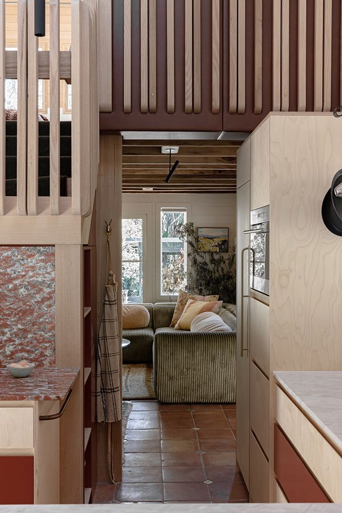 Interior View: Narrow Hallway with Light Timber Cabinets, Terracotta Floor, and Olive Green Sofa in the Living Room — BSpoke Cabinet Making & Joinery in Unanderra, NSW