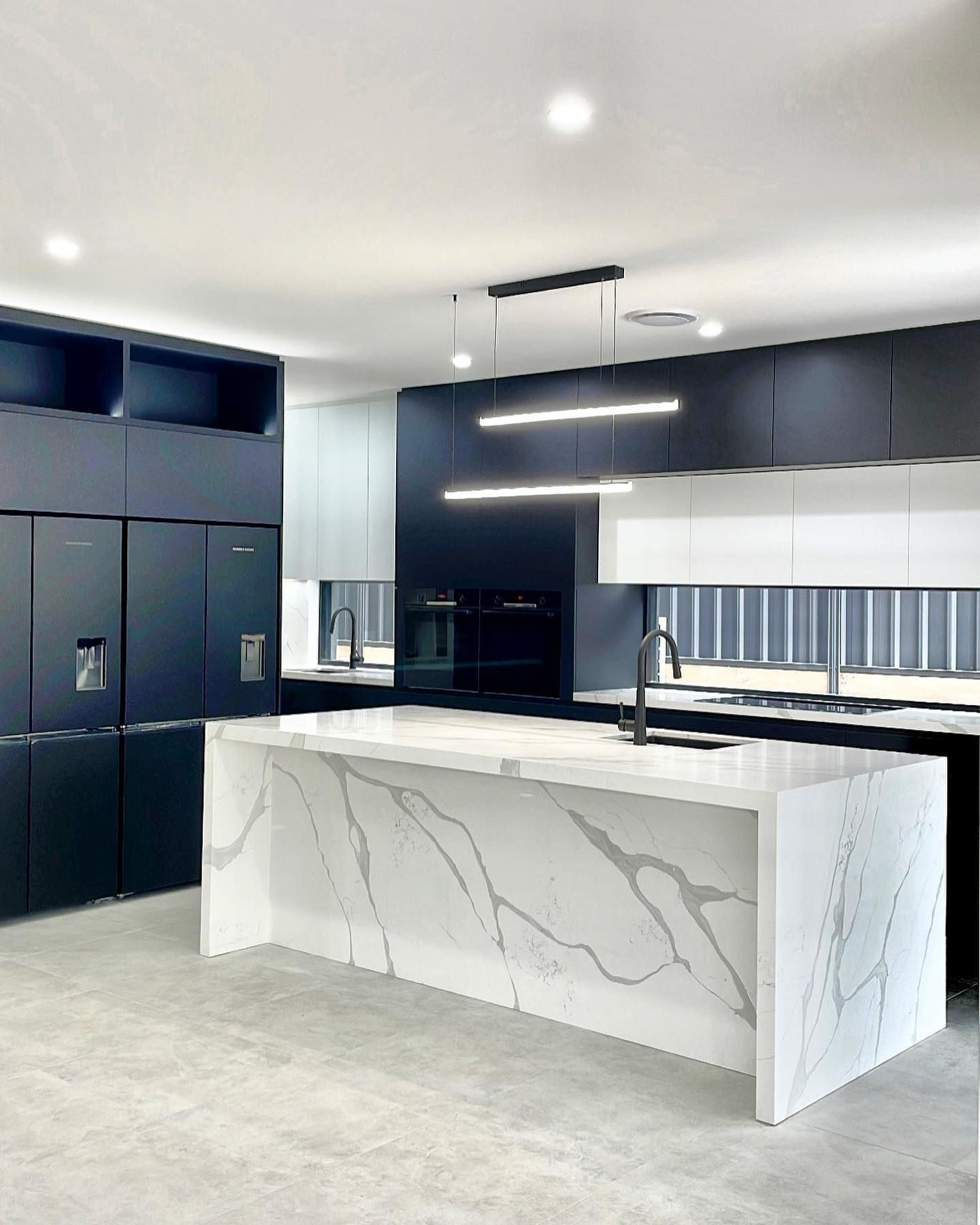 Modern kitchen with white and black cabinets, marble island countertop, and black appliances — BSpoke Cabinet Making & Joinery in Shellharbour, NSW