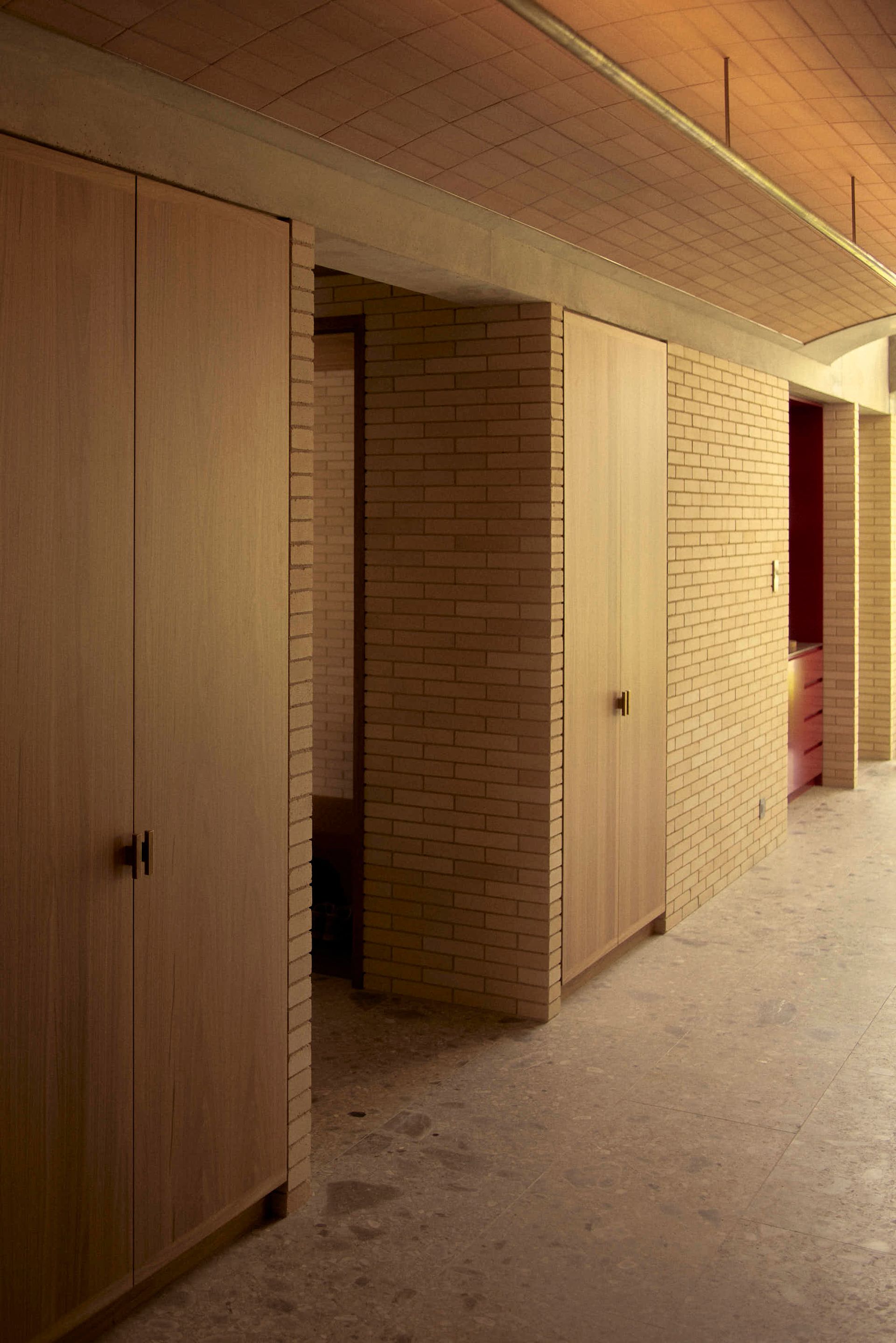 Hallway with brick walls, wooden doors, and exposed ceiling — BSpoke Cabinet Making & Joinery in Southerland Shire, NSW