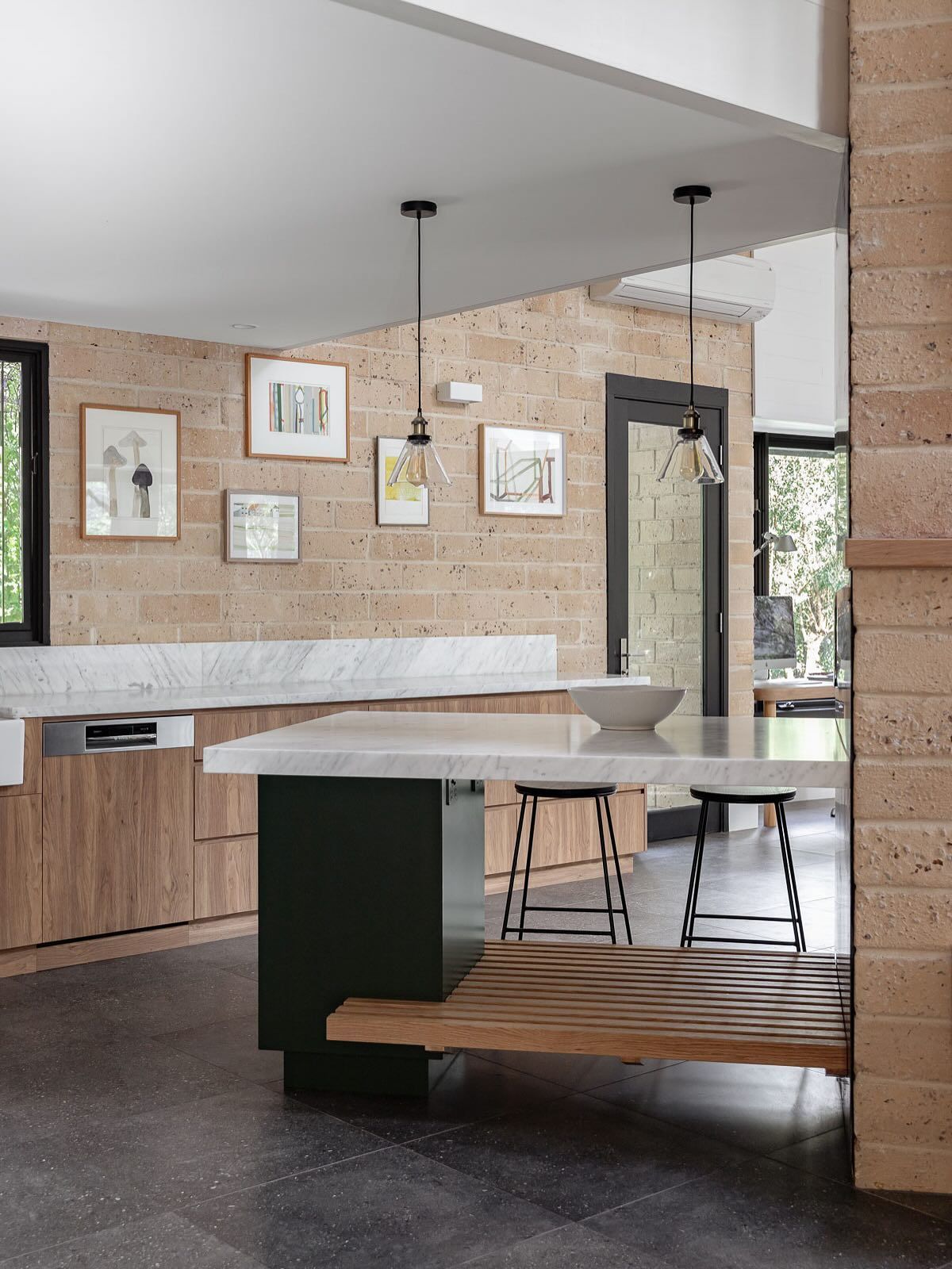 Modern kitchen with stone walls, island, wooden cabinets, and art — BSpoke Cabinet Making & Joinery in Shellharbour, NSW