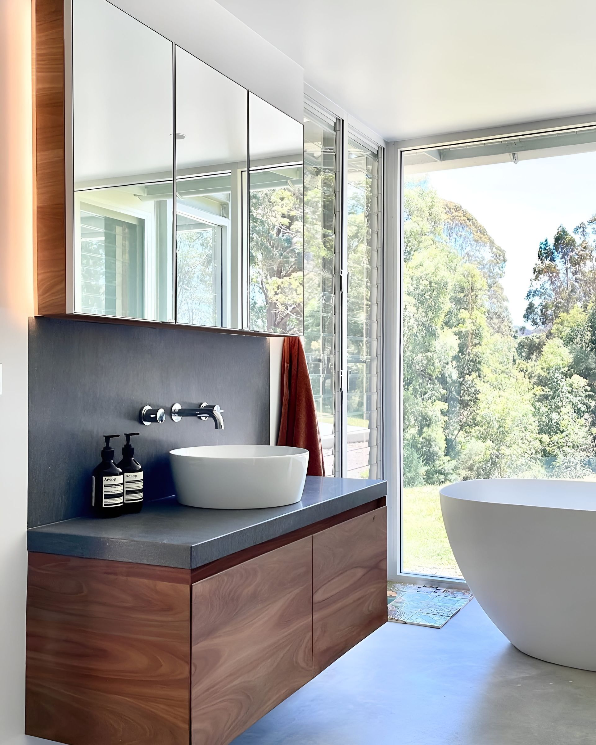 Modern bathroom with wood vanity, vessel sink, large mirror, and soaking tub with a scenic view — BSpoke Cabinet Making & Joinery in Shellharbour, NSW