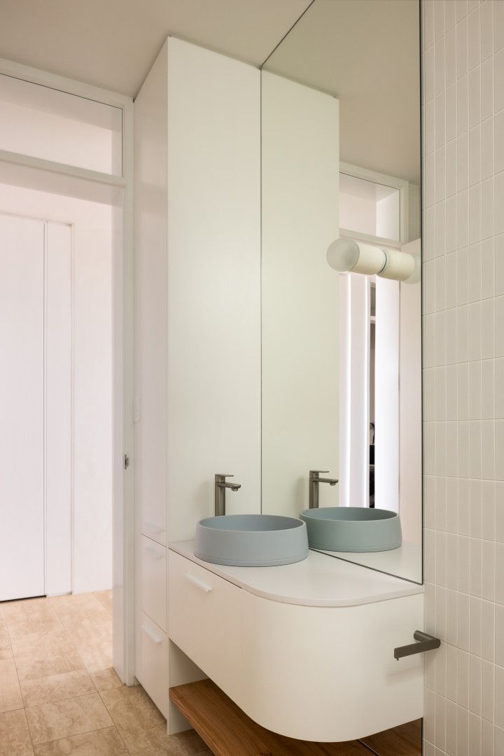 White modern bathroom with a curved vanity, blue sink, and tall storage cabinet — BSpoke Cabinet Making & Joinery in Shellharbour, NSW