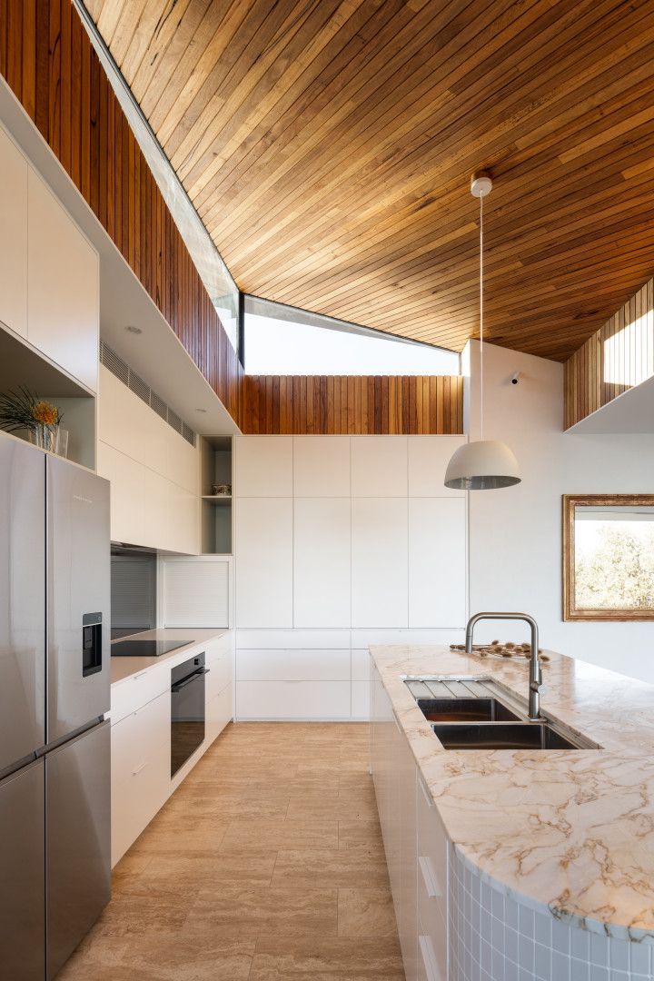 Modern white kitchen with wood ceiling and a marble island — BSpoke Cabinet Making & Joinery in Unanderra, NSW