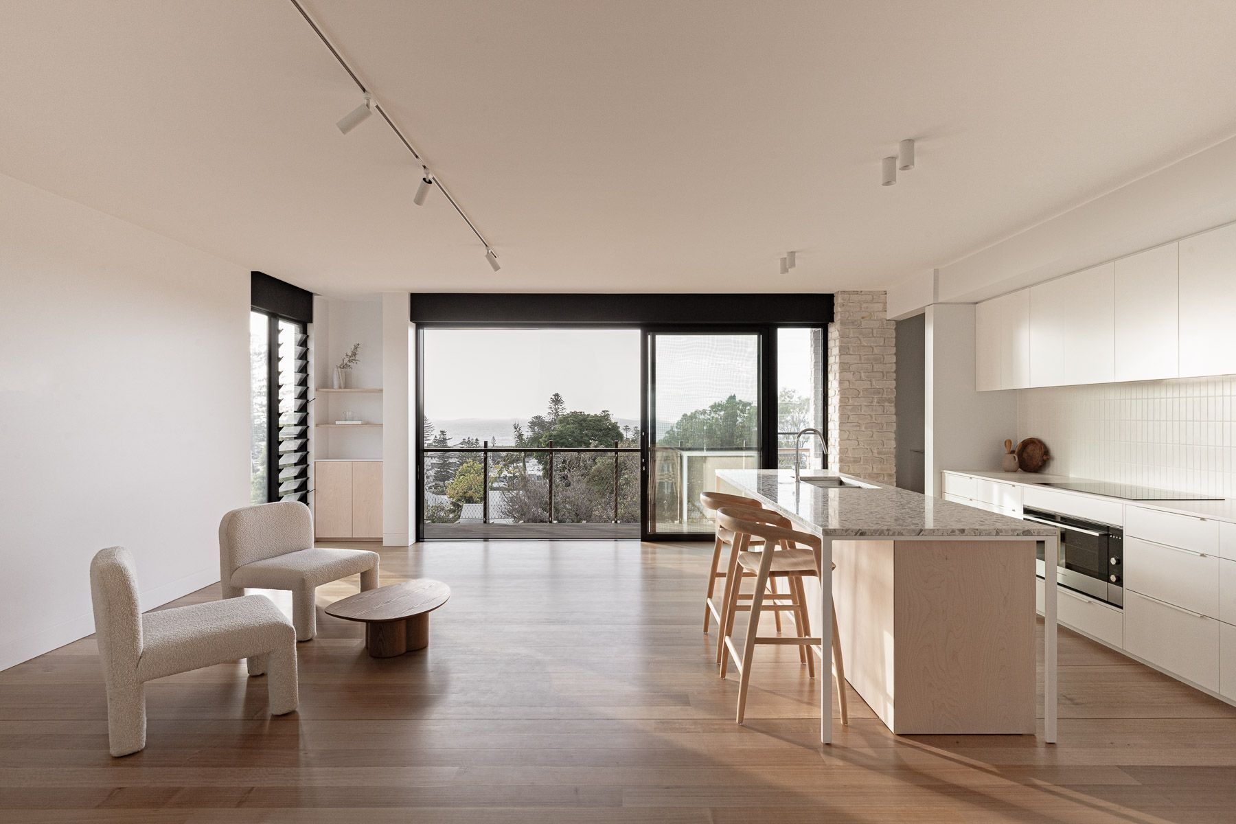 Bright kitchen with island and bar stools, leading to a balcony with an outdoor view — BSpoke Cabinet Making & Joinery in Unanderra, NSW
