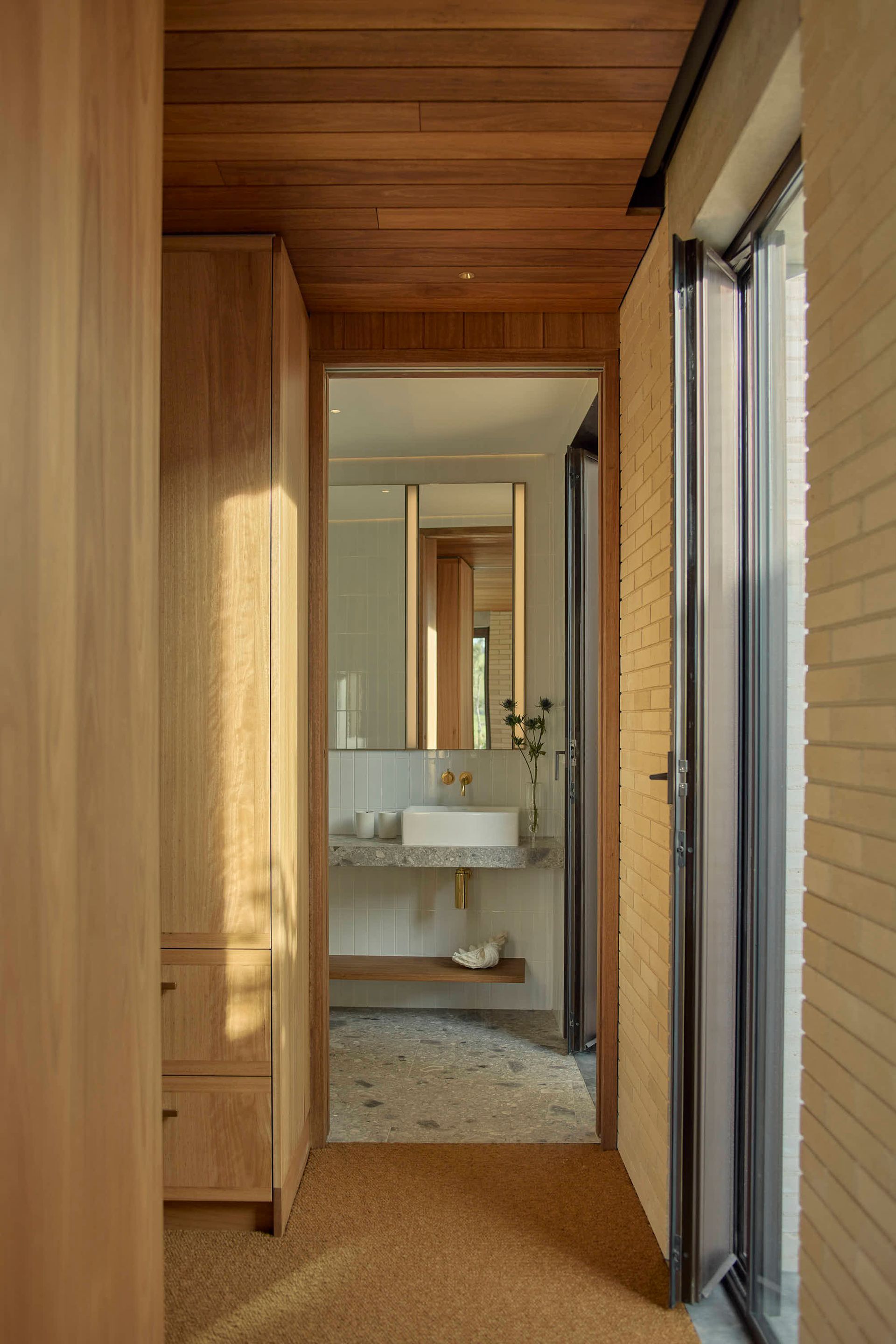 Hallway with wooden ceiling and closet, leading to a bathroom with a sink and mirror — BSpoke Cabinet Making & Joinery in Unanderra, NSW