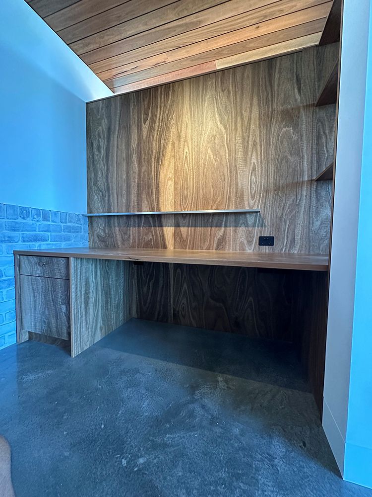 Wooden Built-in Desk in Room with Blue Walls, Grey Floor, and Shelves — BSpoke Cabinet Making & Joinery in Unanderra, NSW