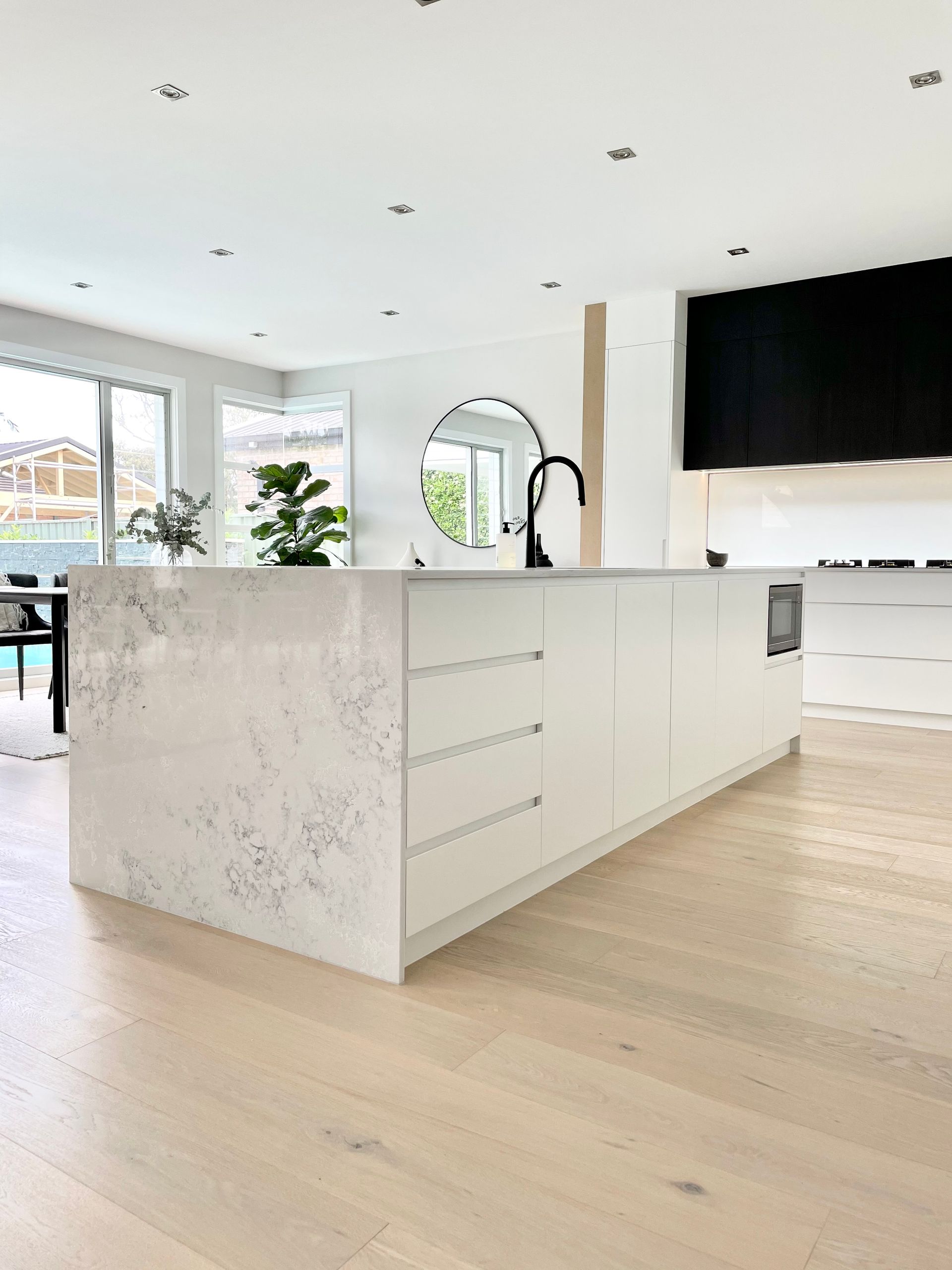 Modern kitchen with a white island, light wood floors, and a black faucet — BSpoke Cabinet Making & Joinery in Unanderra, NSW