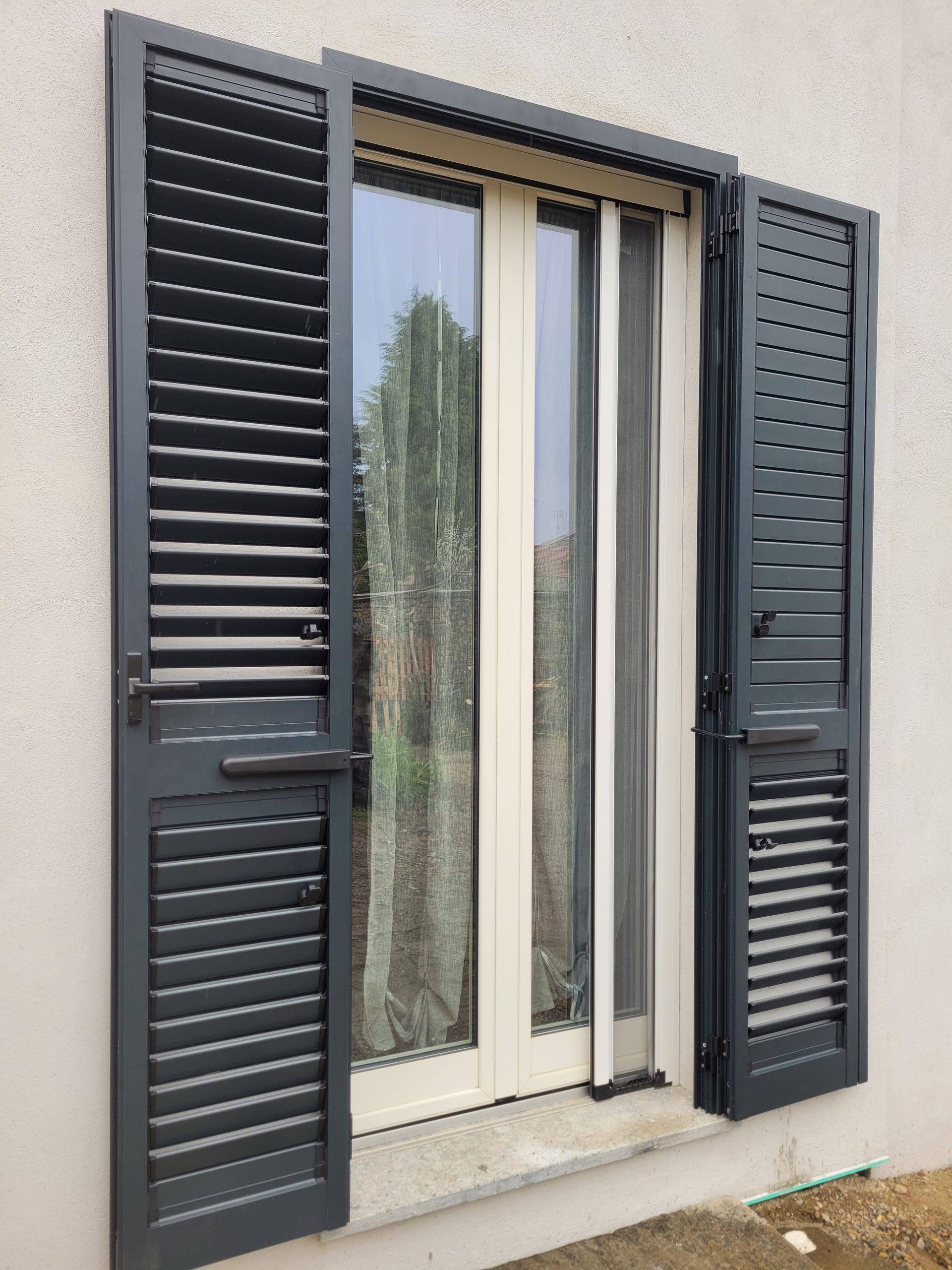 Una finestra con persiane e una porta scorrevole in vetro.