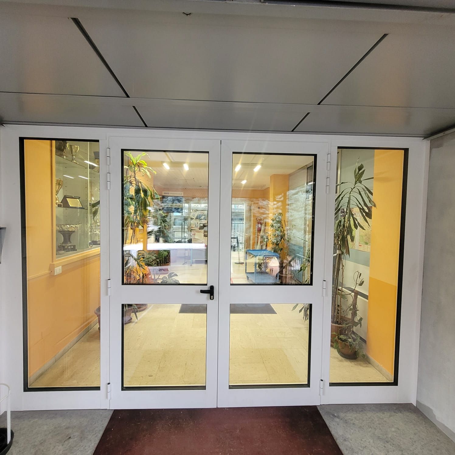 Una porta a vetri con un tappetino rosso davanti