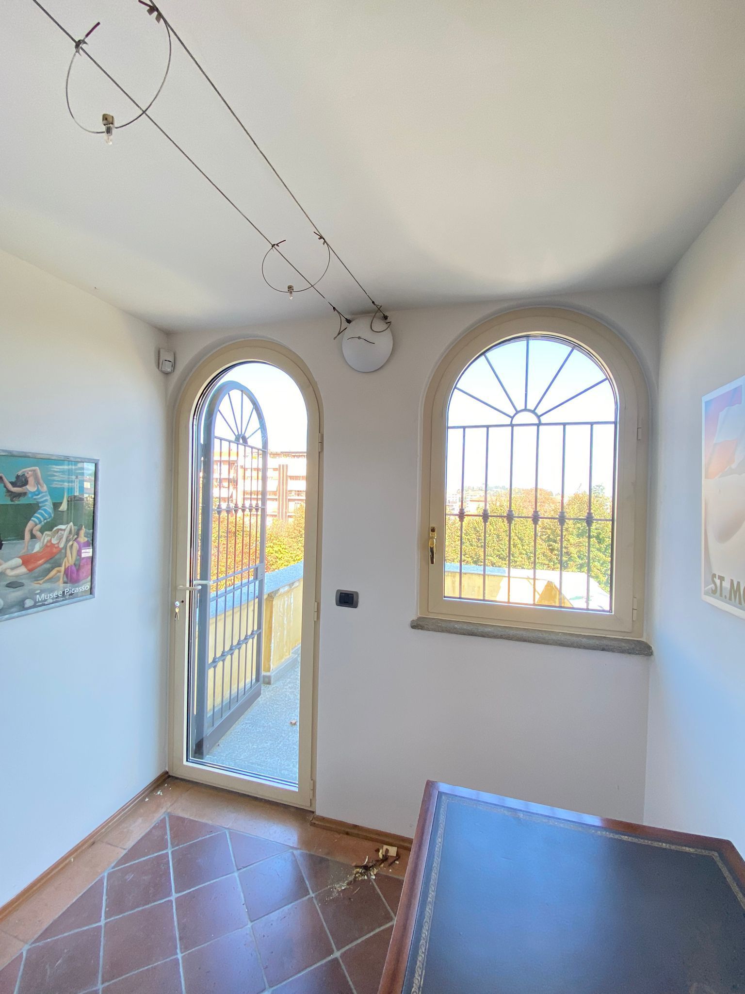 Una stanza con due finestre ad arco e un orologio sul soffitto