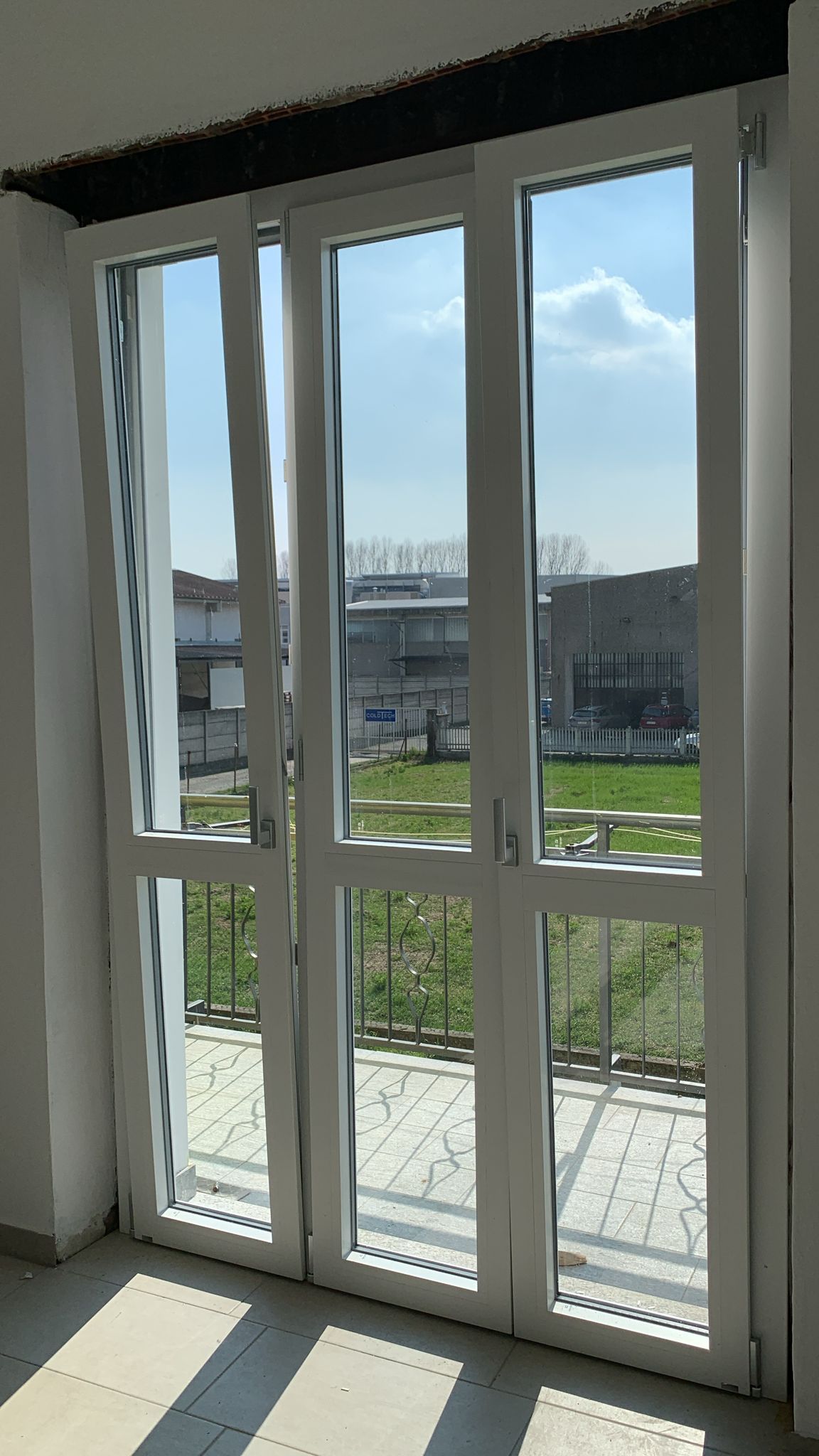 Una stanza con molte finestre e un balcone.