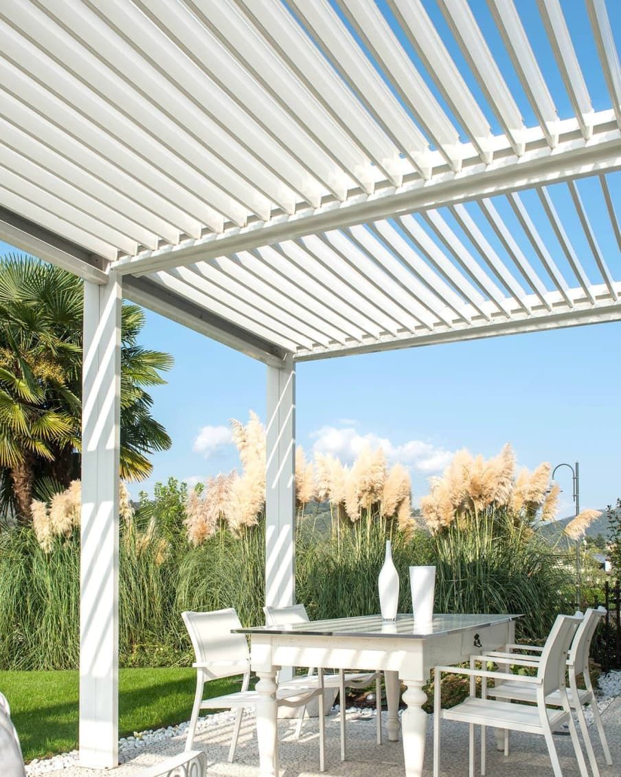 Un pergolato bianco con un tavolo e delle sedie sotto