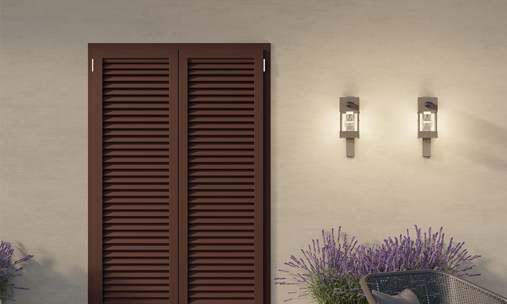 Una porta con le persiane si trova accanto a un vaso di fiori viola.