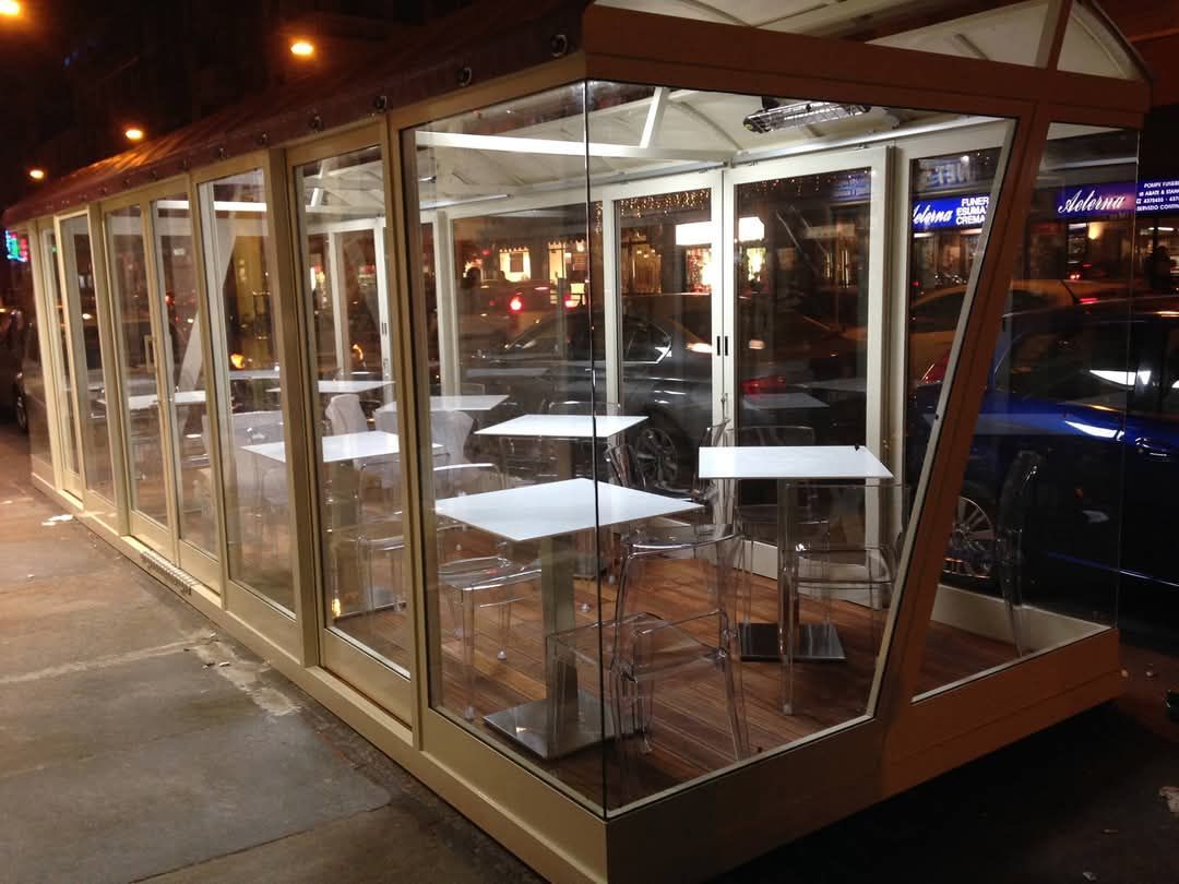 Un edificio di vetro con tavoli e sedie al suo interno