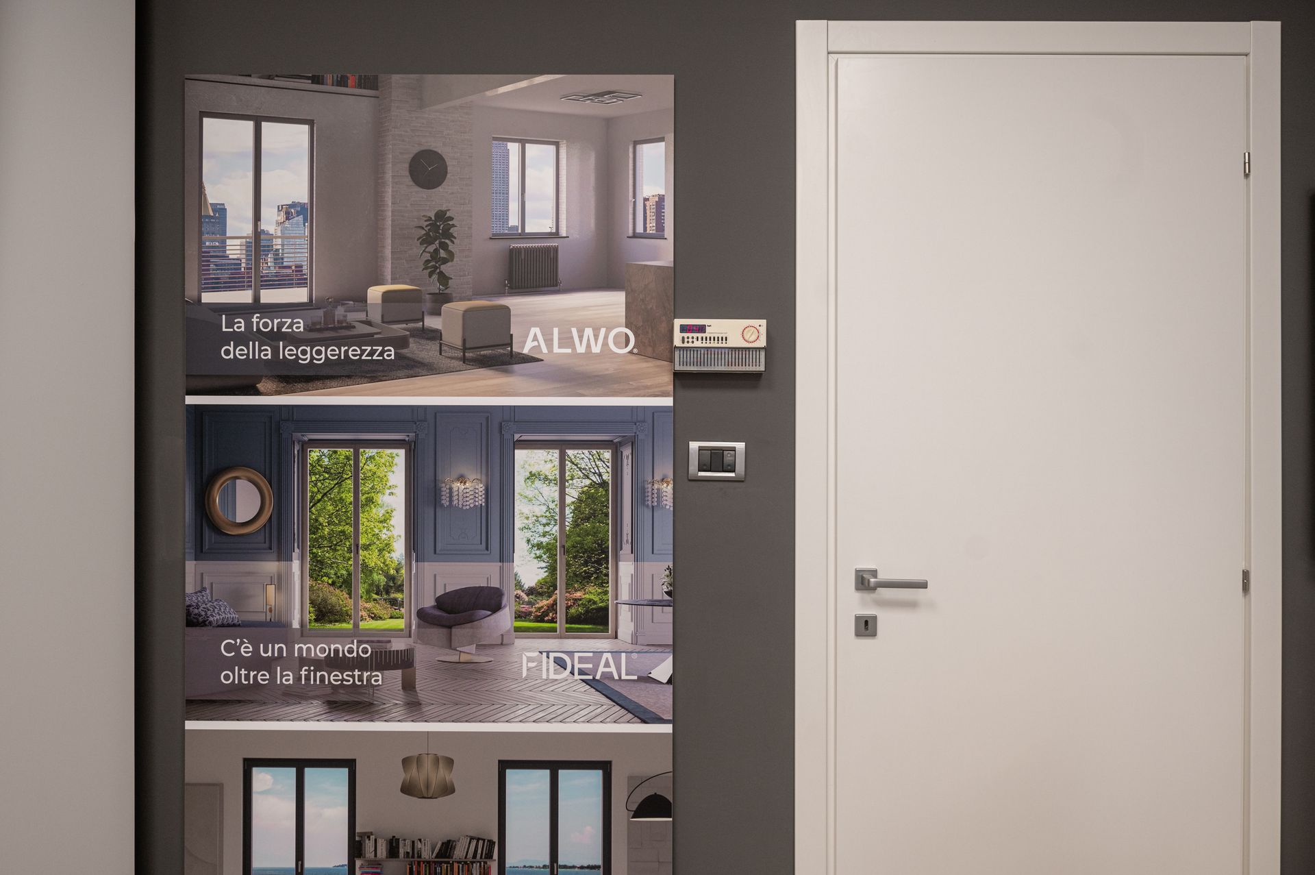 Una porta bianca è appoggiata a una parete su cui sono appese le foto di un soggiorno e di una camera da letto.