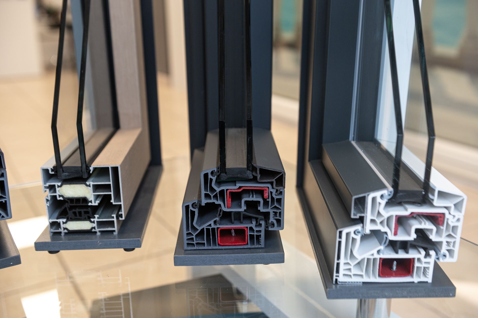 Un'esposizione di diversi tipi di finestre di plastica su un tavolo di vetro.