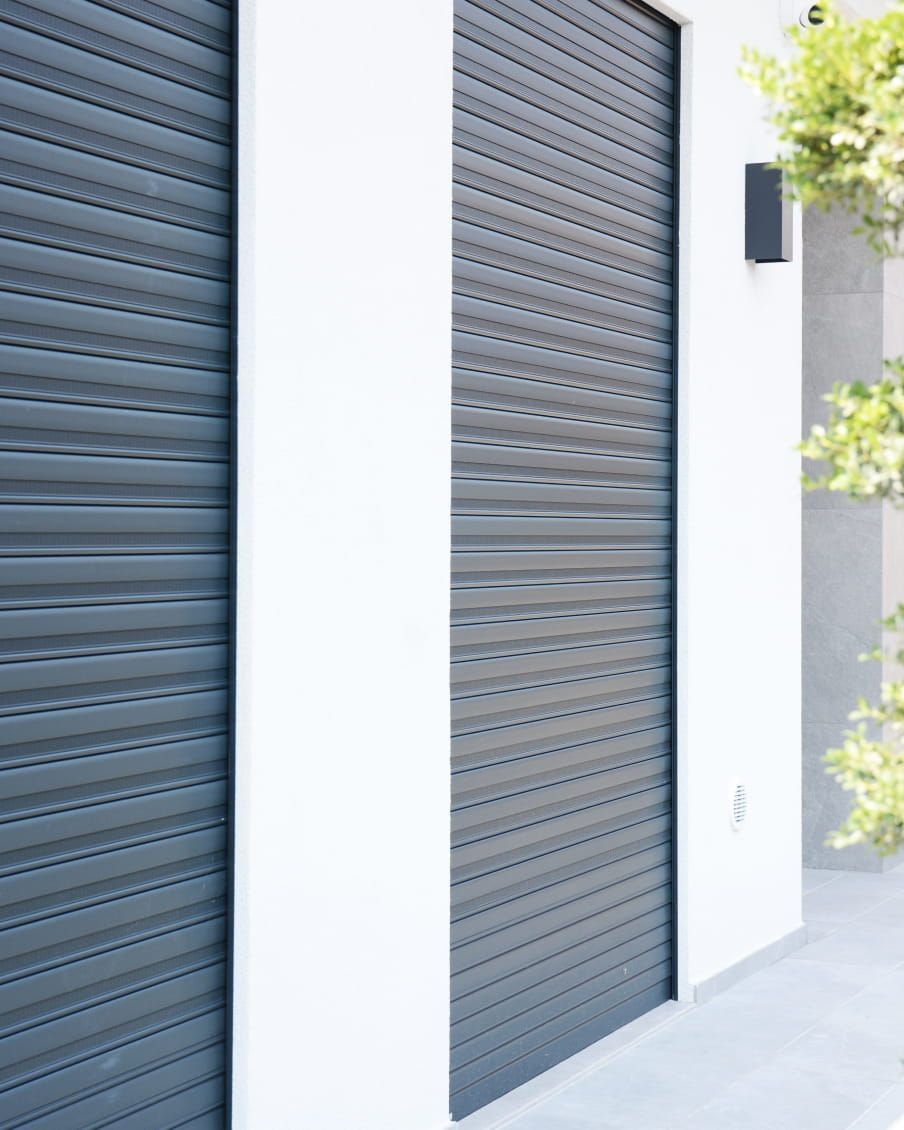 Una finestra con persiane verdi e piante in vaso sul davanzale.