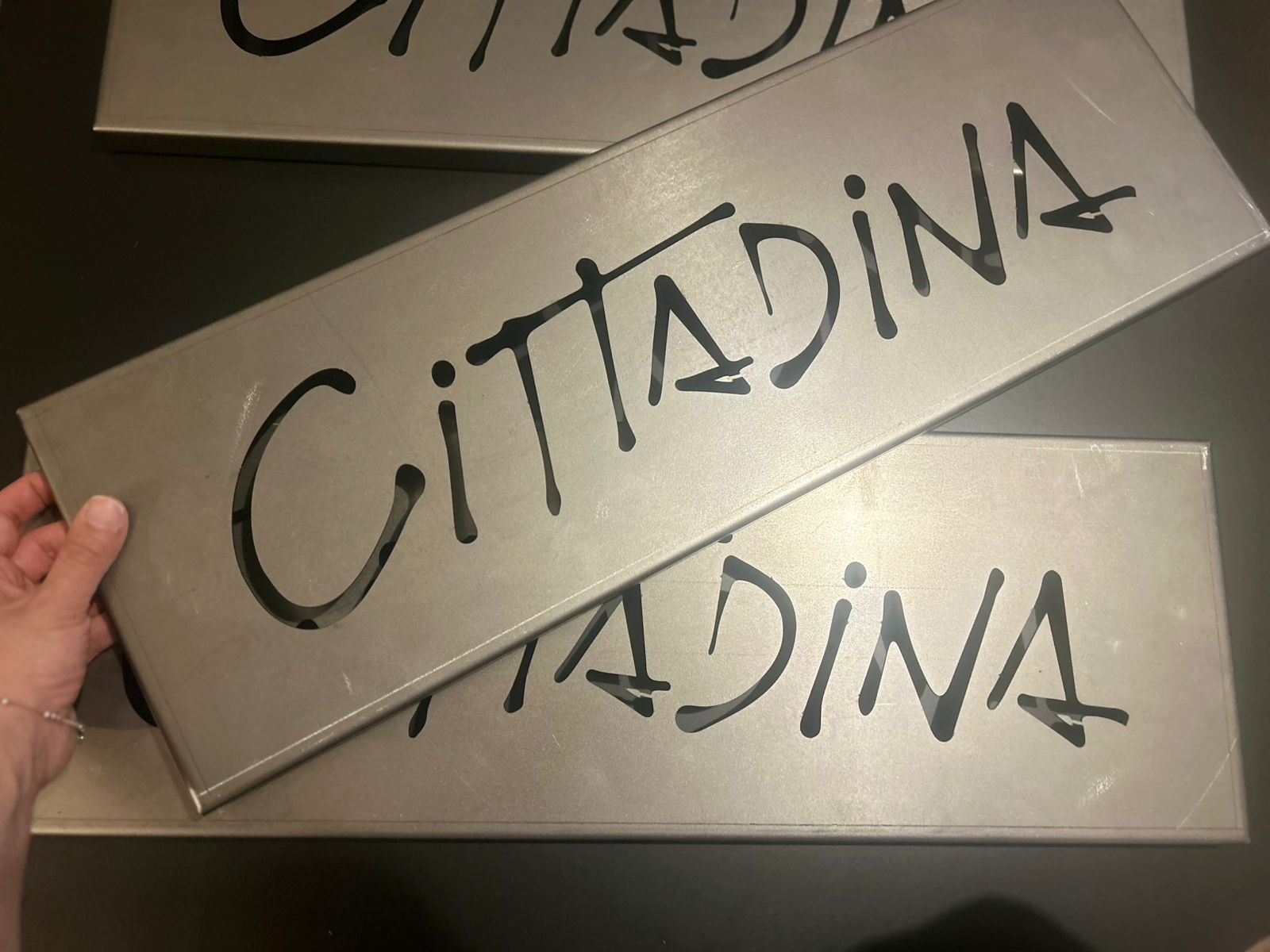 Mano sosteniendo un cartel metálico con la palabra 