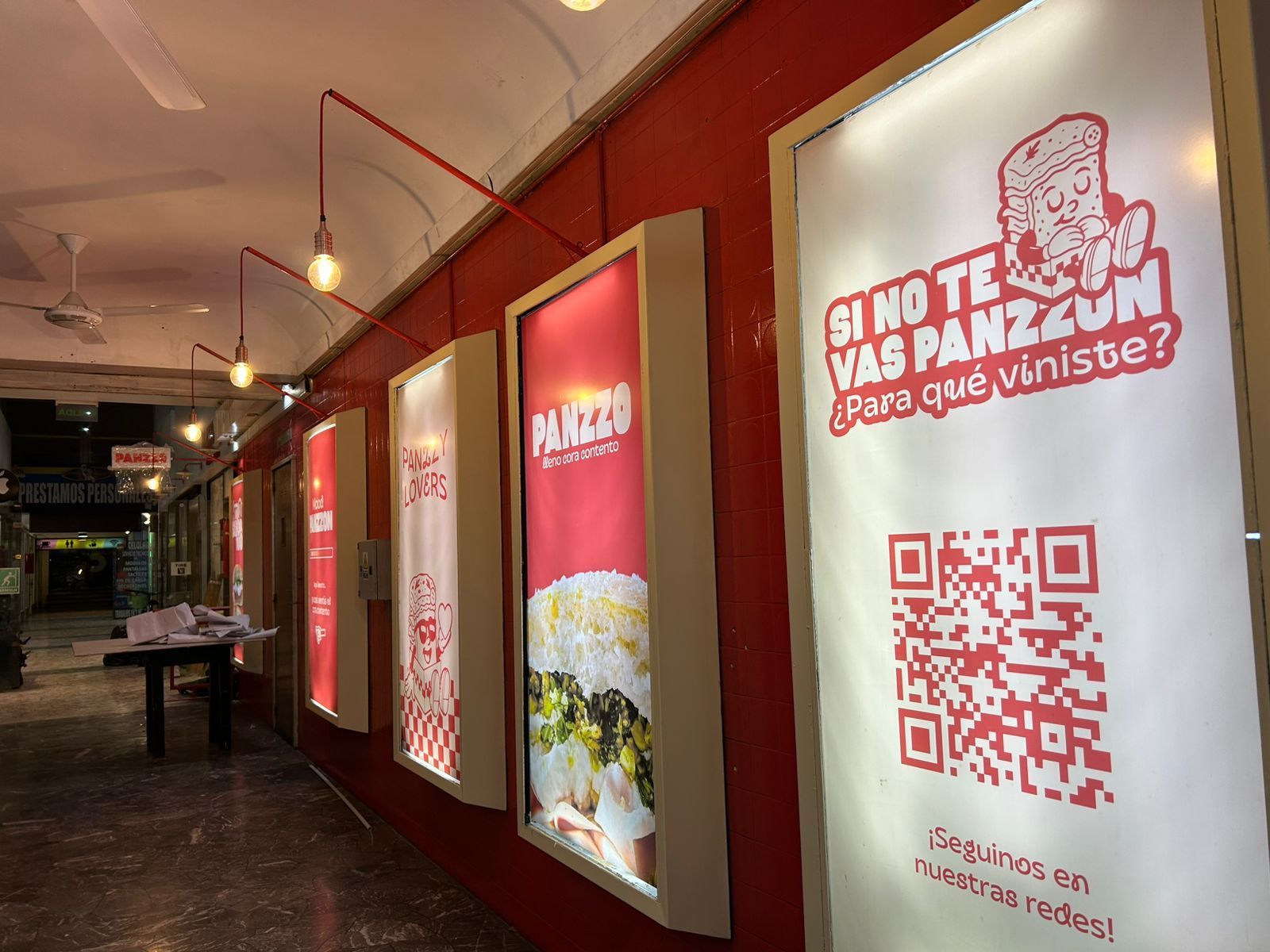 Interior de tienda de alimentación de temática roja con anuncios iluminados. Código QR y texto