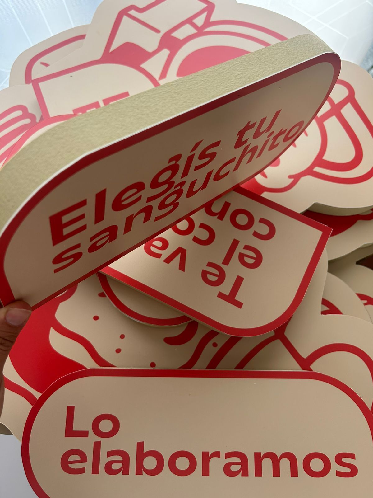 Letreros con texto rojo sobre fondo beige; dice 