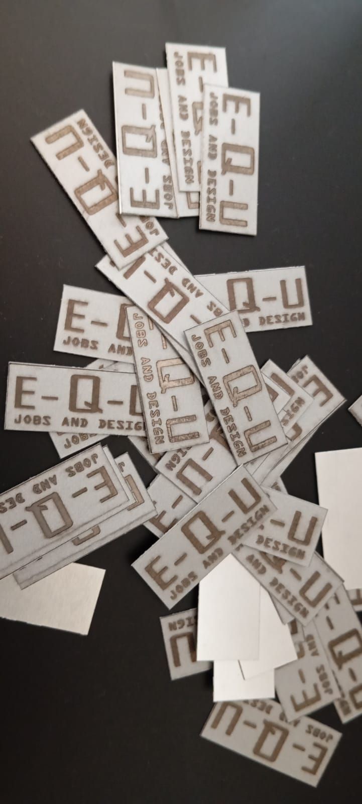 Pila de etiquetas rectangulares blancas y grises, cada una impresa con las letras 