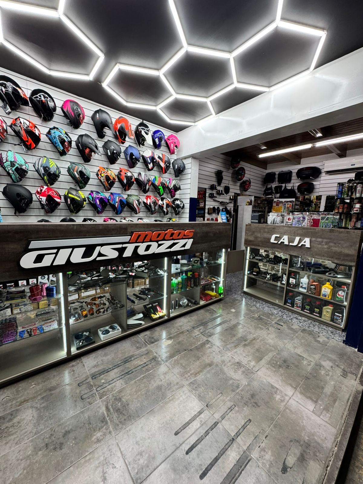 Interior de tienda de artículos para motocicletas con cascos en exhibición y el cartel 