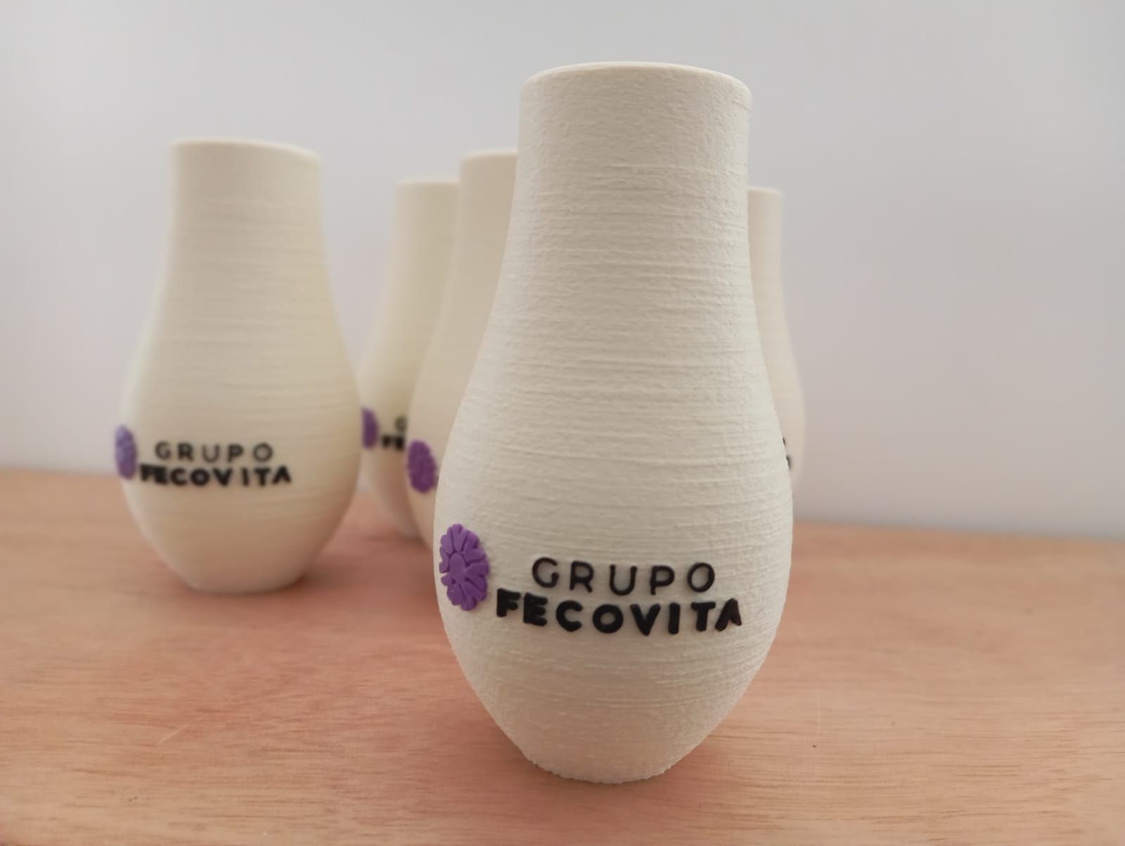 Un grupo de jarrones blancos con la palabra grupo en ellos están sobre una mesa de madera.