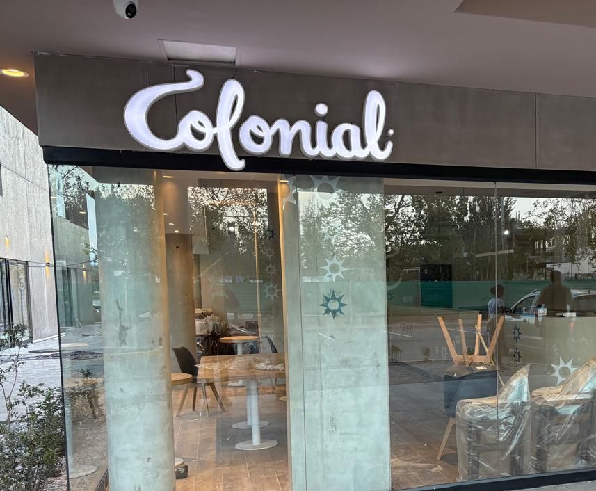 El frente de un restaurante colonial con mesas y sillas.