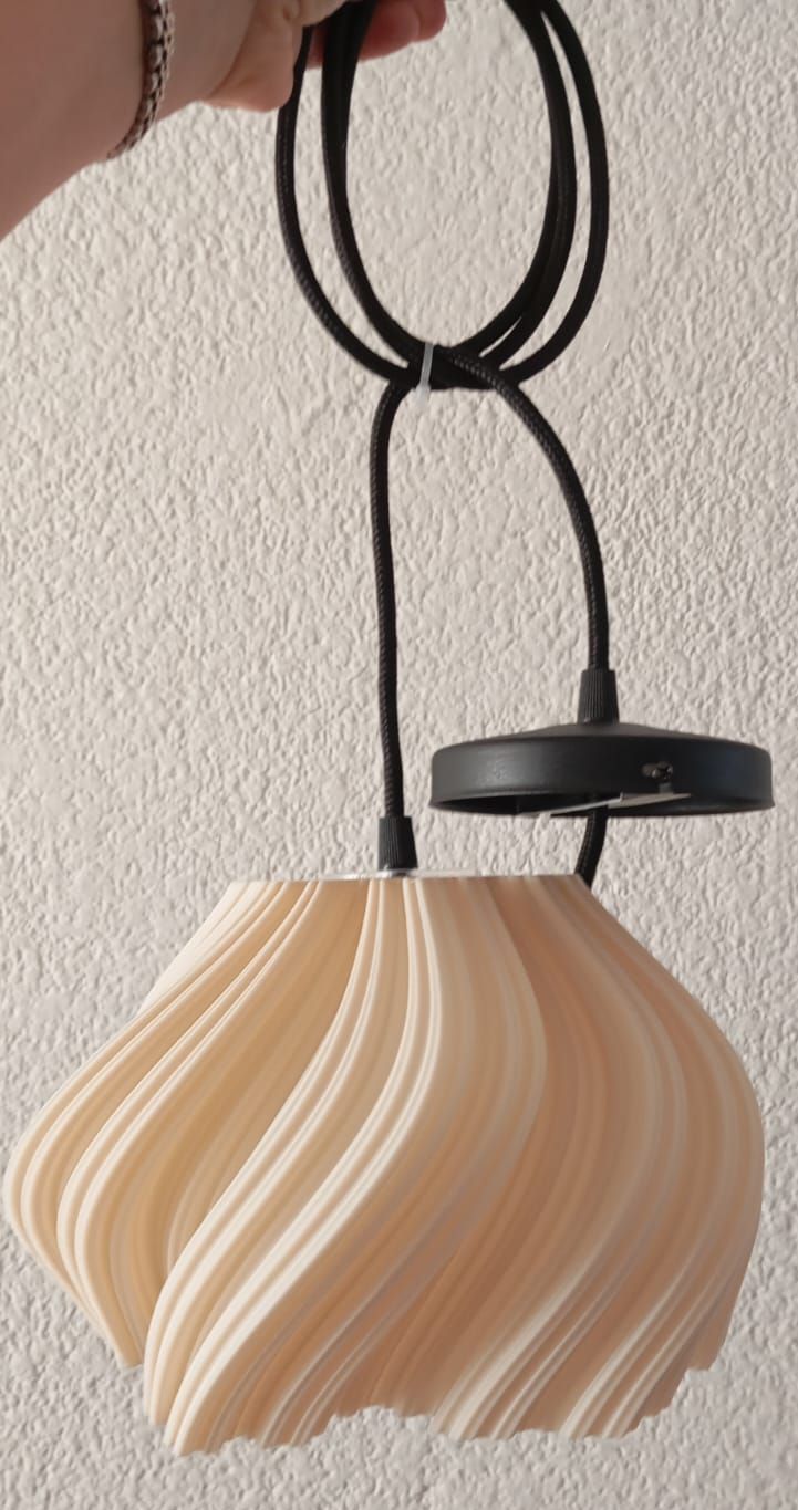Una persona sostiene una lámpara colgante con un cable negro.