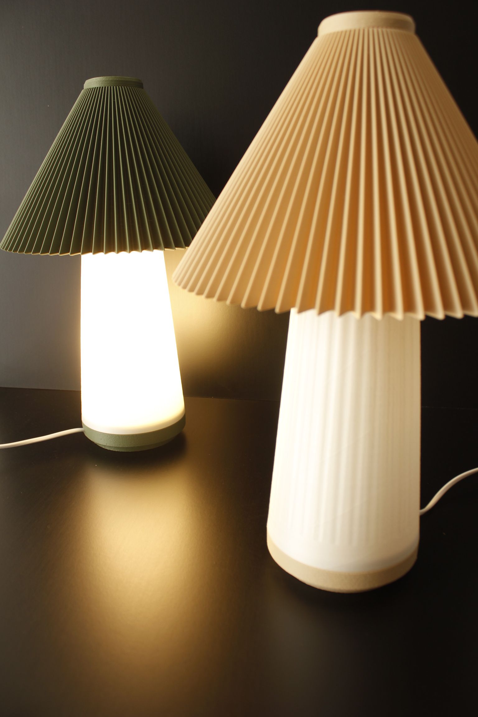Dos lámparas con pantallas plisadas están sobre una mesa.