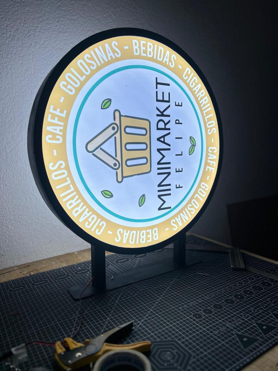 Letrero de minimercado redondo iluminado con texto en español, incluido 