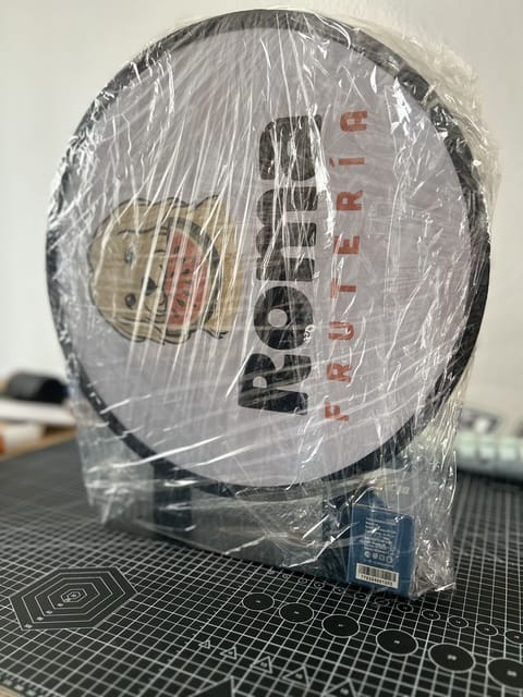 Letrero redondo para frutería, envuelto en plástico, con texto y un personaje de dibujos animados