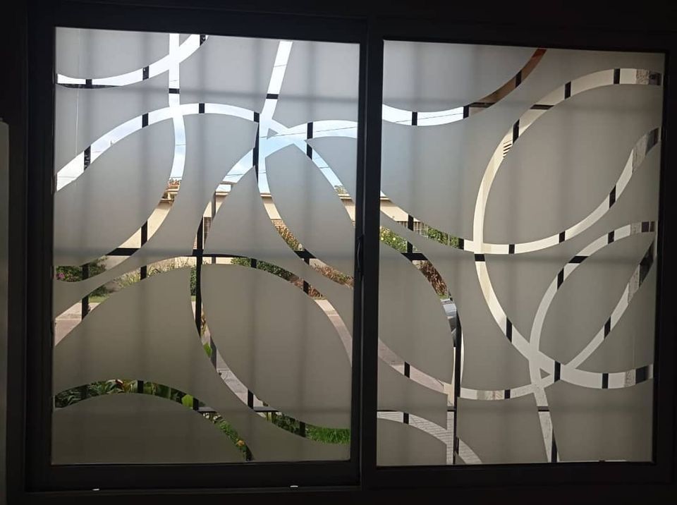 Ventana de vidrio esmerilado con diseño de ondas abstractas; marco oscuro, fondo exterior visible.