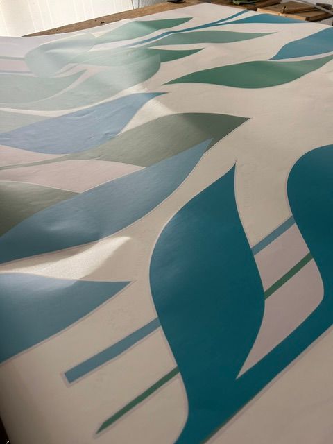 Patrón abstracto de formas de hojas de color verde azulado, azul y verde sobre un fondo blanco.