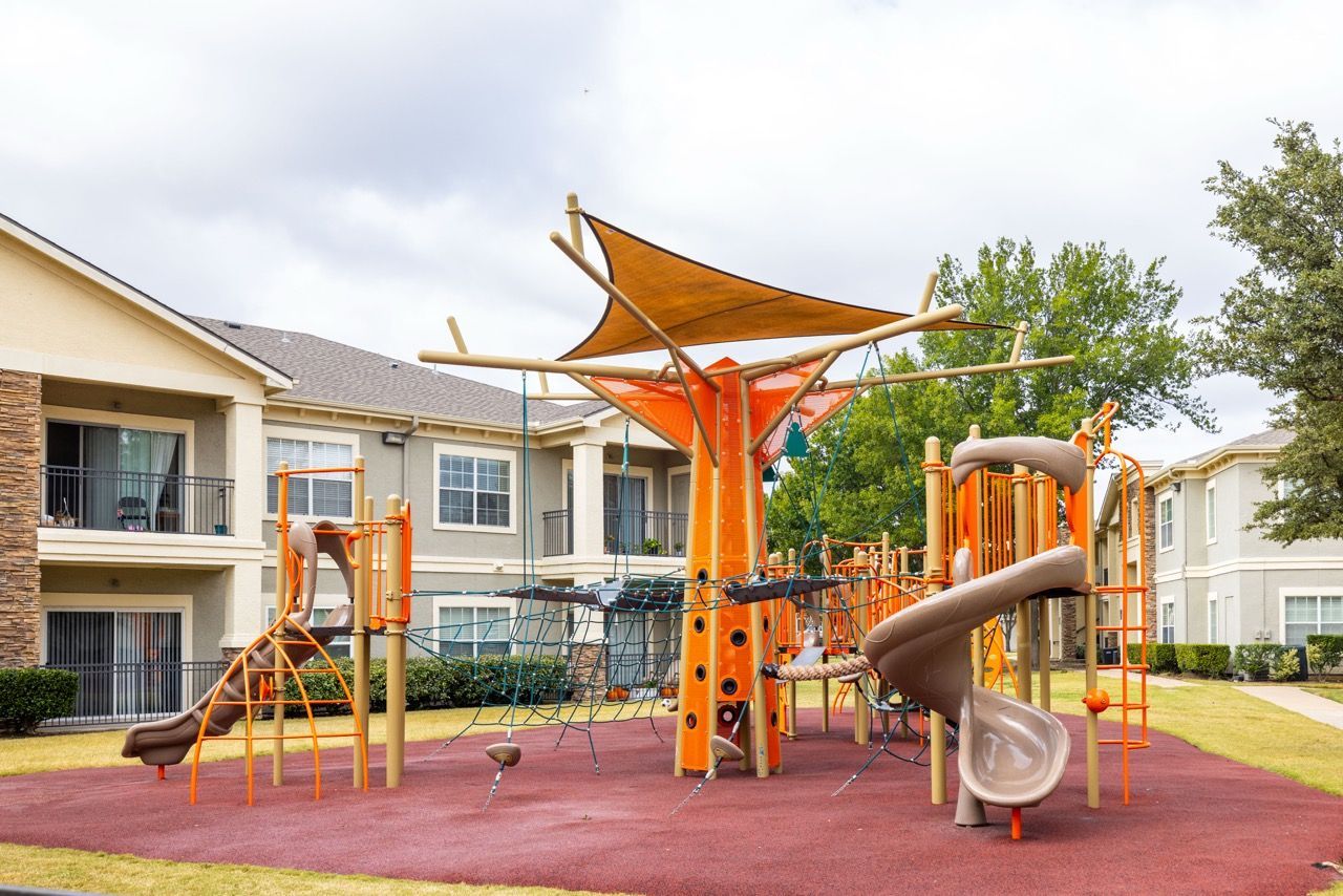 Colorful outdoor playground with slides and climbing structures in an apartment community courtyard.