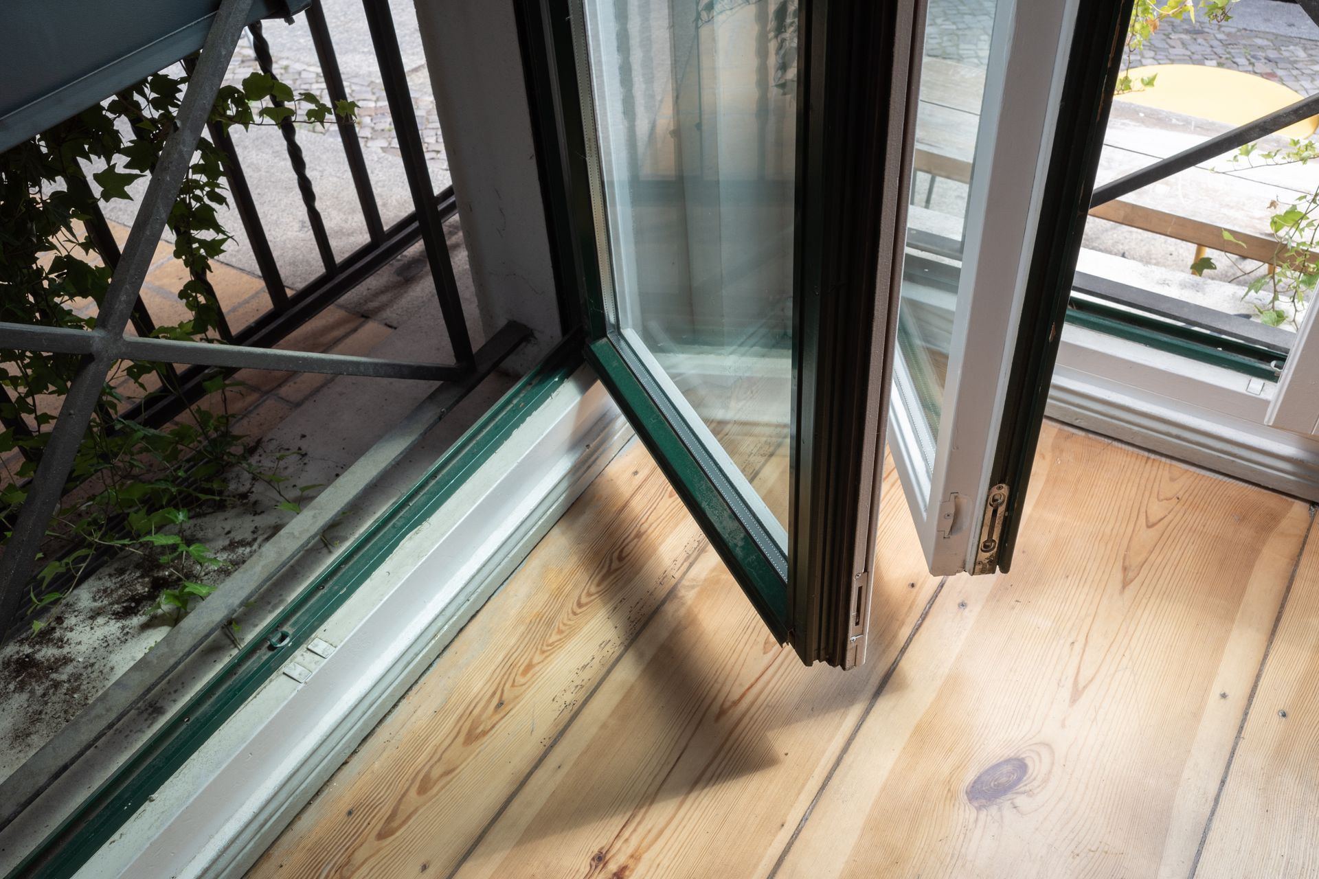 Open balcony door with wooden floor and metal railing outside — Kracken Windows and Doors In Manly, NSW