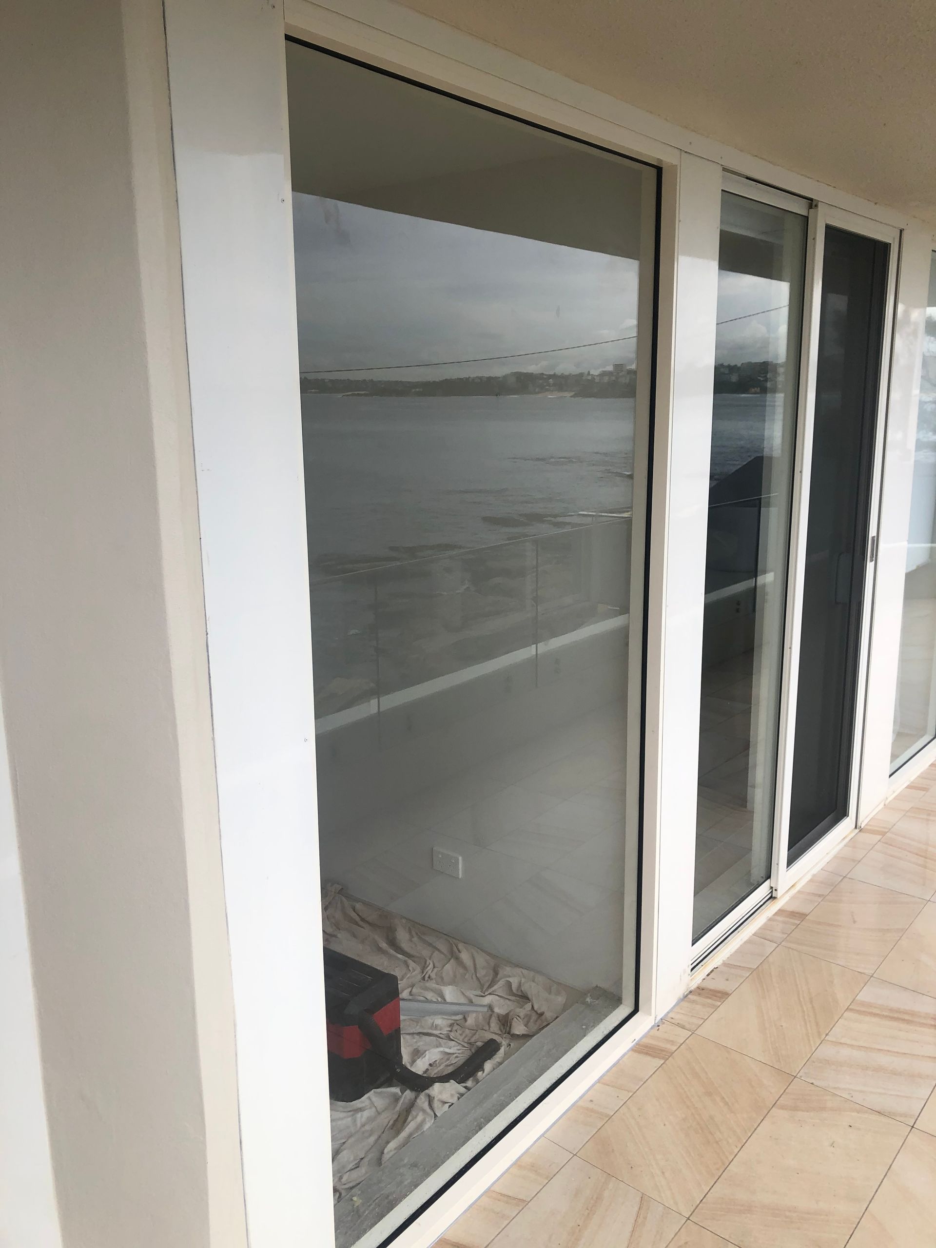 Sliding glass doors overlooking a waterfront, with beige tiled walkway outside. — Kracken Windows and Doors In Terrey Hills, NSW