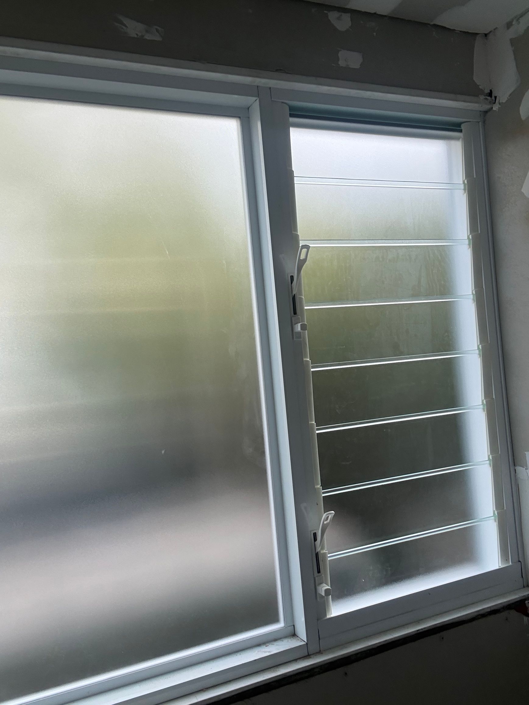 Frosted sliding window with one pane open, showing exterior louvers on the right — Kracken Windows and Doors In Terrey Hills, NSW