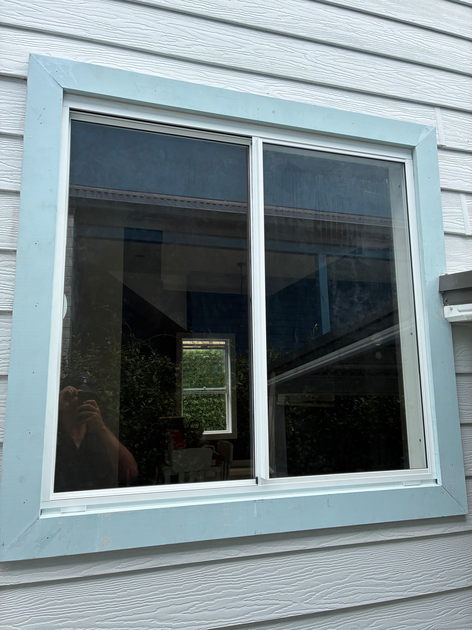 White-framed window in a pale blue wall, reflecting an outdoor scene. — Kracken Windows and Doors In Terrey Hills, NSW