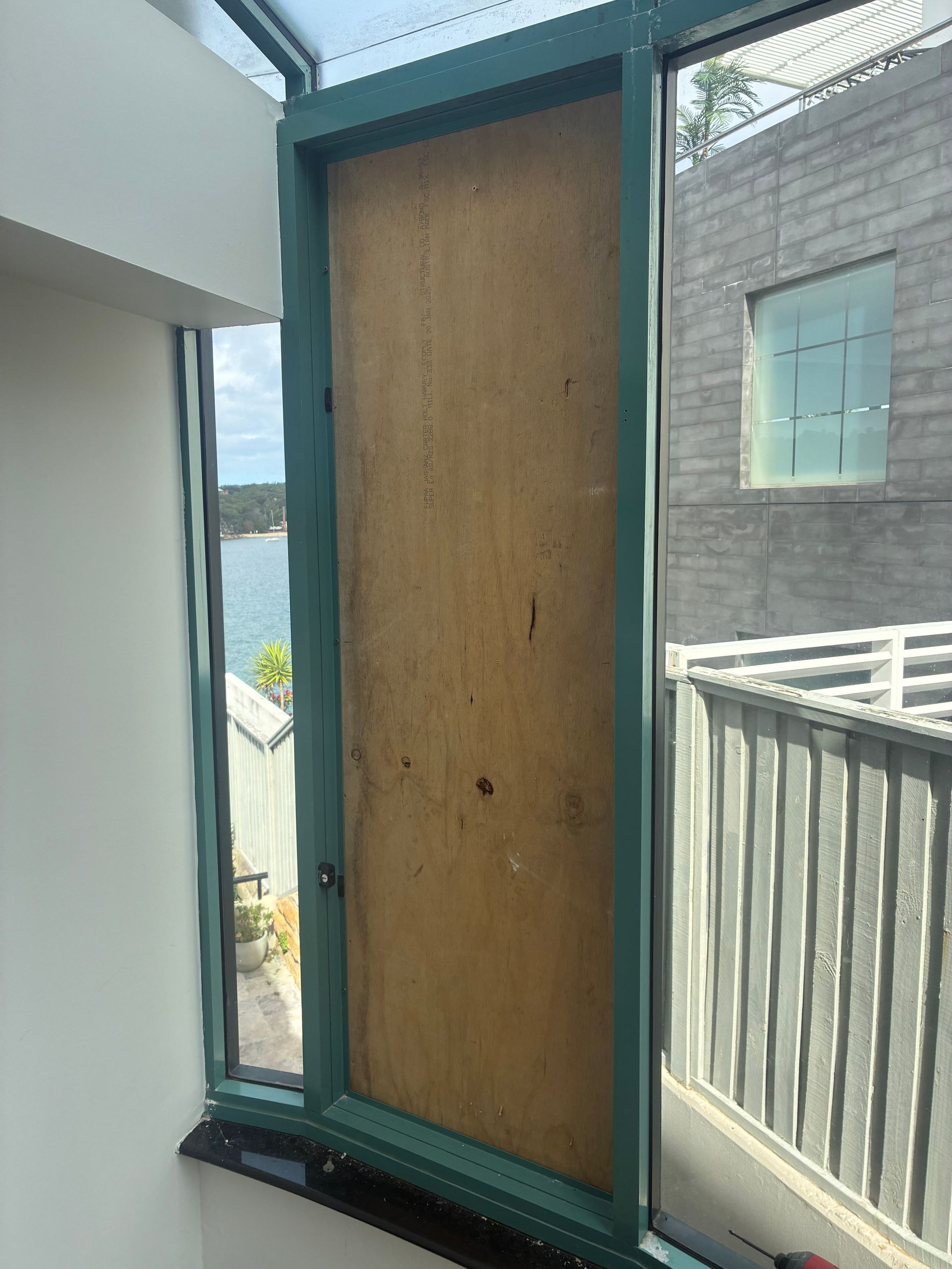 Tall boarded-up doorway with teal frame in a narrow outdoor corridor — Kracken Windows and Doors In Terrey Hills, NSW