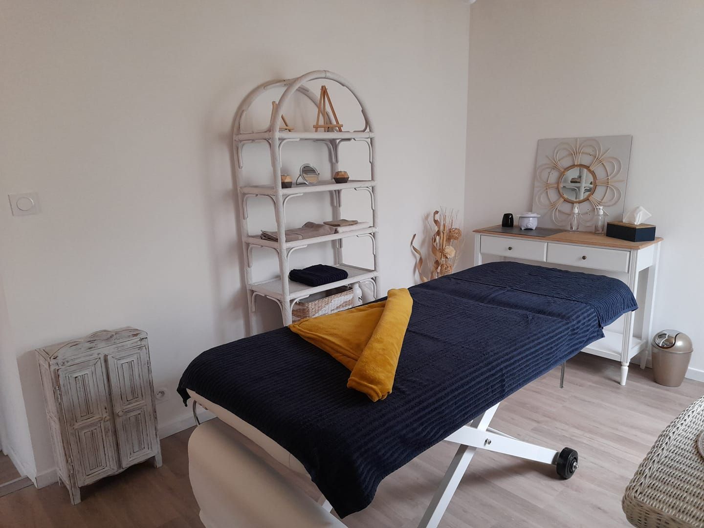 Une table de massage avec une couverture bleue et un oreiller jaune dans une pièce.