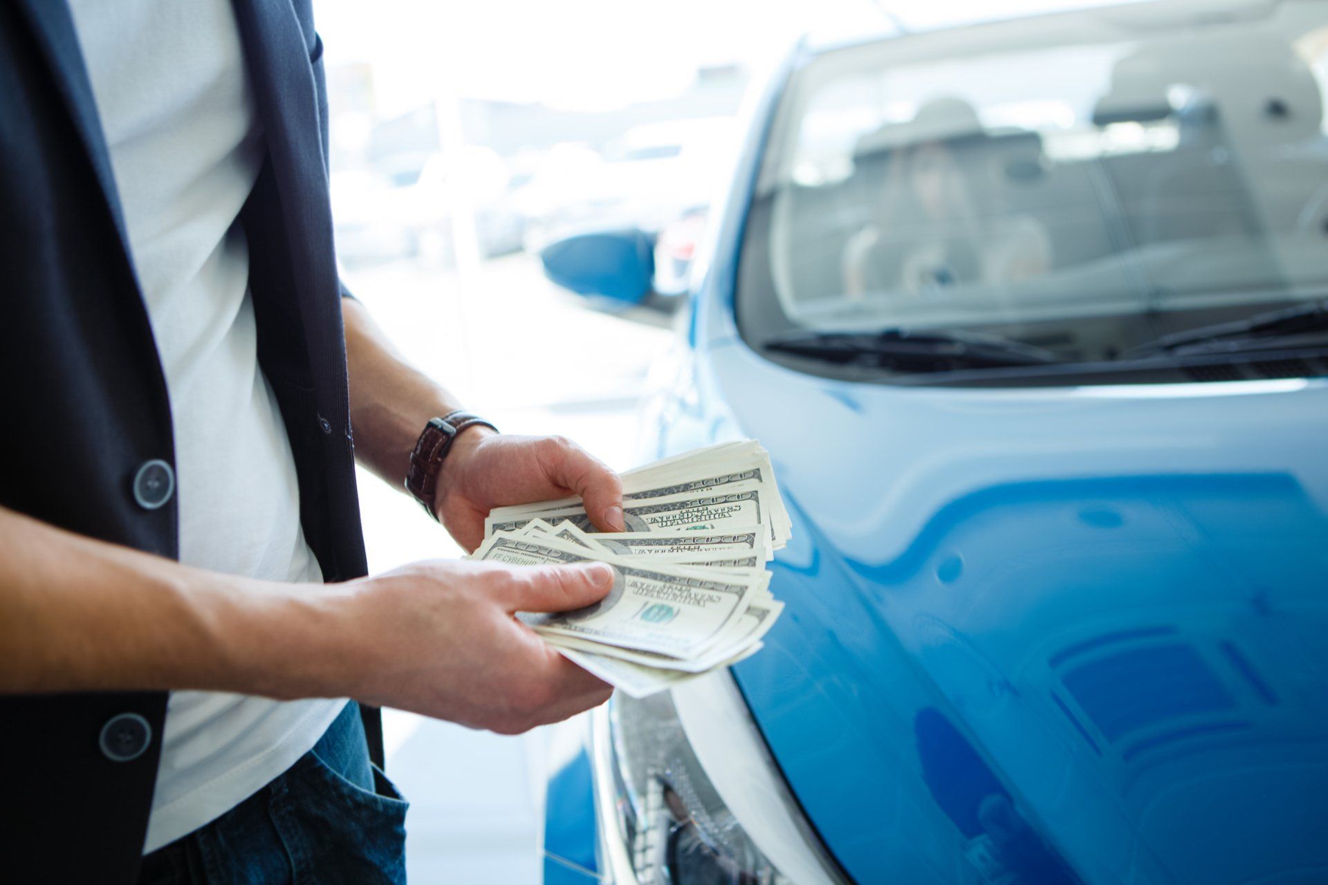 man holding cash in hands near car